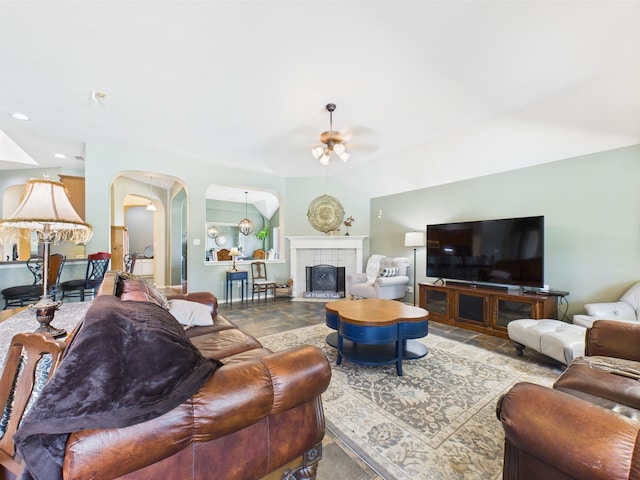 1409 Stoney Hills Dr, Cedar Hill, TX 75104 - living area featuring ceiling fan, arched walkways, vaulted ceiling, stone finish flooring, and a tile fireplace