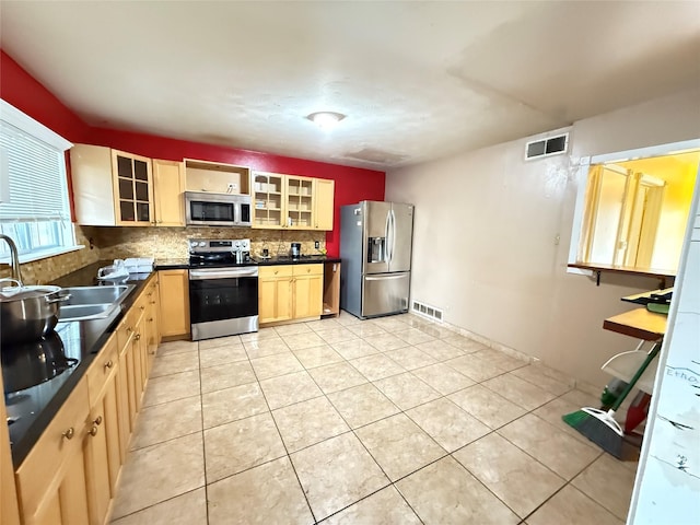 3106 Marydale Rd, Garland, TX 75041 - kitchen with stainless steel appliances, a sink, light brown cabinetry, dark countertops, and tasteful backsplash