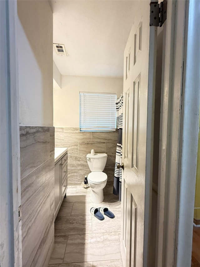 3106 Marydale Rd, Garland, TX 75041 - full bathroom with tile walls, vanity, toilet, and a wainscoted wall