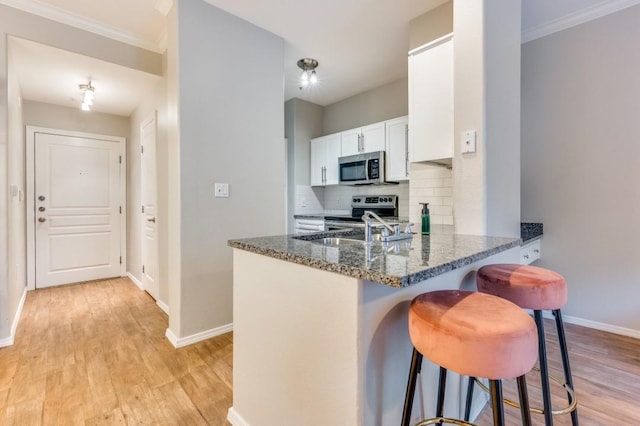 330 Las Colinas Blvd E Unit 140, Irving, TX 75039 - kitchen with stainless steel appliances, a breakfast bar area, dark stone counters, decorative backsplash, and light wood finished floors