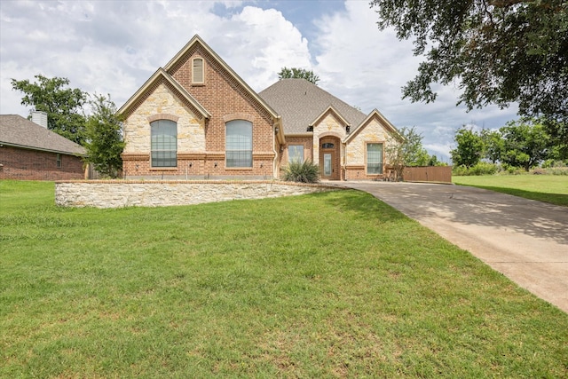 7017 Westover Dr, Granbury, TX 76049 - french country inspired facade featuring a front lawn, brick siding, stone siding, and concrete driveway