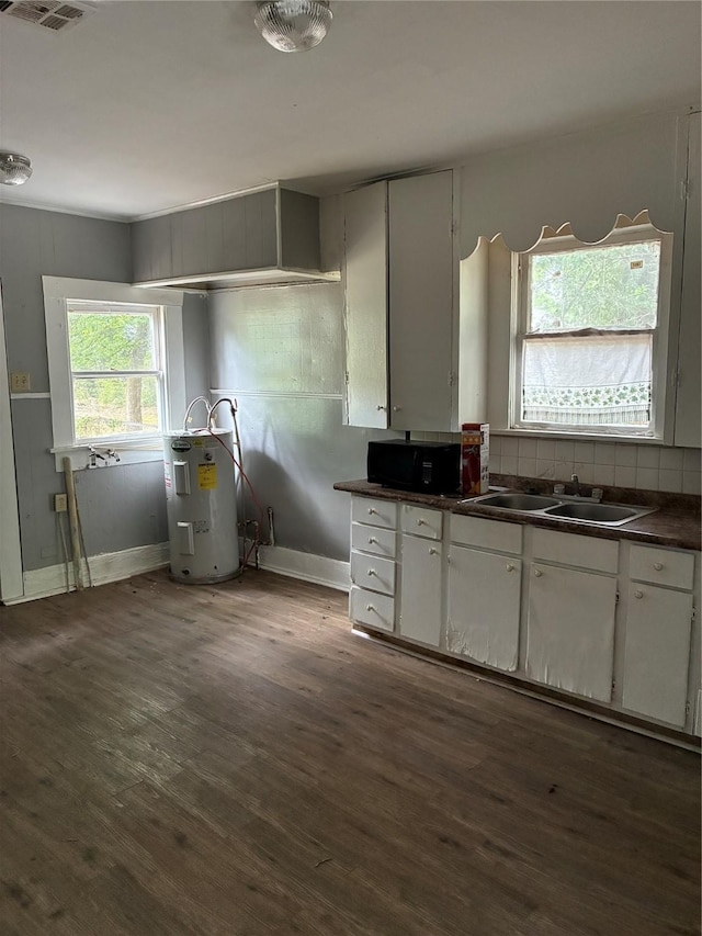 3014 Desoto St, Shreveport, LA 71109 - kitchen featuring water heater, dark countertops, dark wood-style flooring, a sink, and white cabinetry