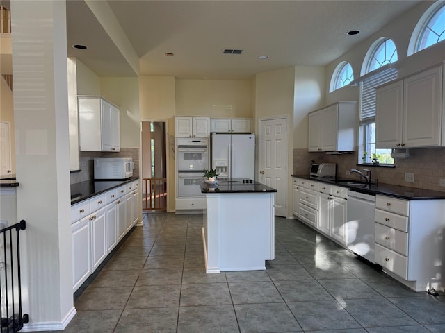 2802 Sunrise Dr, Rowlett, TX 75088 - kitchen with white appliances, dark countertops, a center island, backsplash, and white cabinets