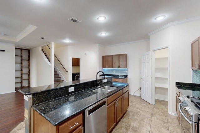 1278 Wysteria Ln, Burleson, TX 76028 - kitchen with stainless steel appliances, a sink, ornamental molding, brown cabinets, and a center island with sink