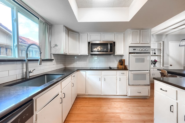2123 Sunrise Trl, Richardson, TX 75081 - kitchen featuring appliances with stainless steel finishes, backsplash, light wood finished floors, a tray ceiling, and white cabinetry