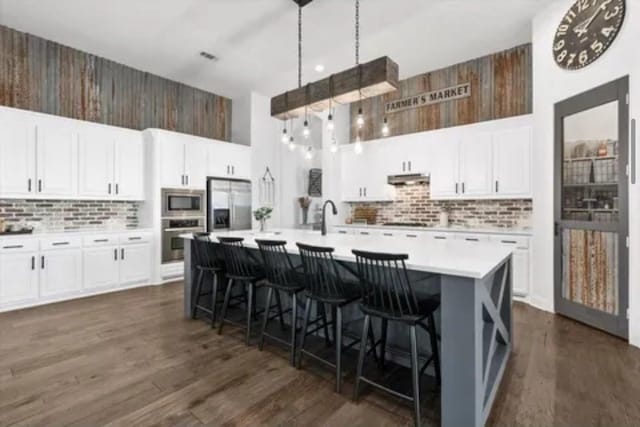 1104 Killian Dr, Mansfield, TX 76063 - kitchen featuring appliances with stainless steel finishes, a towering ceiling, tasteful backsplash, under cabinet range hood, and light countertops