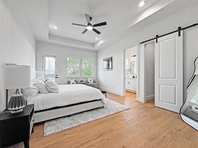 2417 Merlin St, Dallas, TX 75215 - bedroom with a barn door, a raised ceiling, light wood finished floors, recessed lighting, and connected bathroom