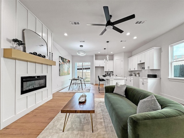 2417 Merlin St, Dallas, TX 75215 - living area with a large fireplace, plenty of natural light, ceiling fan, recessed lighting, and light wood-type flooring