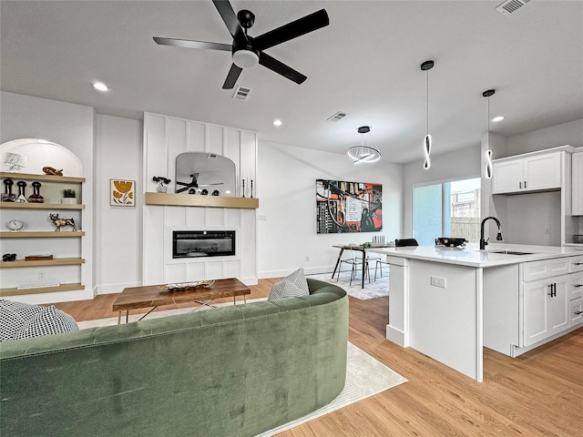 2417 Merlin St, Dallas, TX 75215 - living area with a large fireplace, light wood-type flooring, a ceiling fan, and recessed lighting