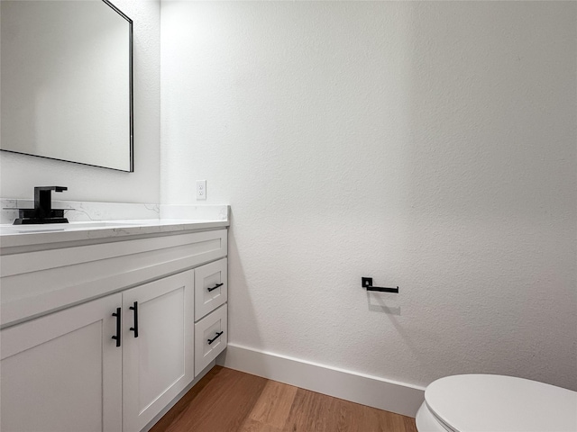 2417 Merlin St, Dallas, TX 75215 - half bathroom with vanity, wood finished floors, baseboards, and toilet