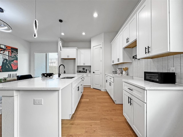 2417 Merlin St, Dallas, TX 75215 - kitchen with a sink, recessed lighting, backsplash, a kitchen island with sink, and light wood finished floors