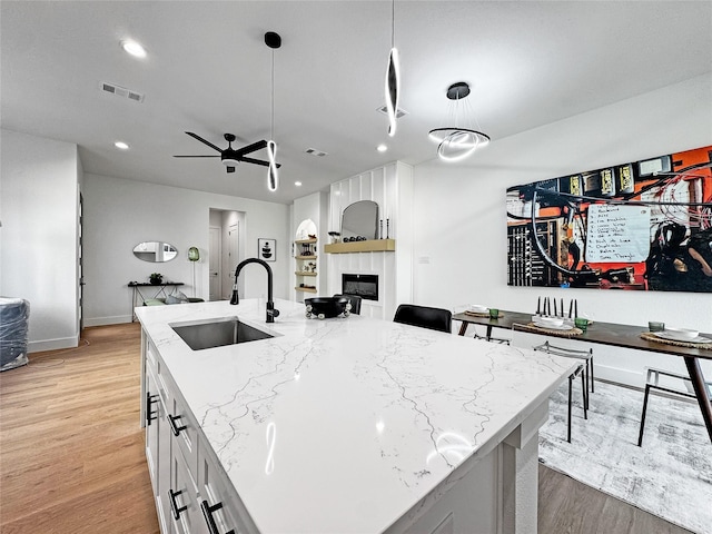 2417 Merlin St, Dallas, TX 75215 - kitchen featuring a sink, light wood-type flooring, light stone countertops, open floor plan, and a fireplace