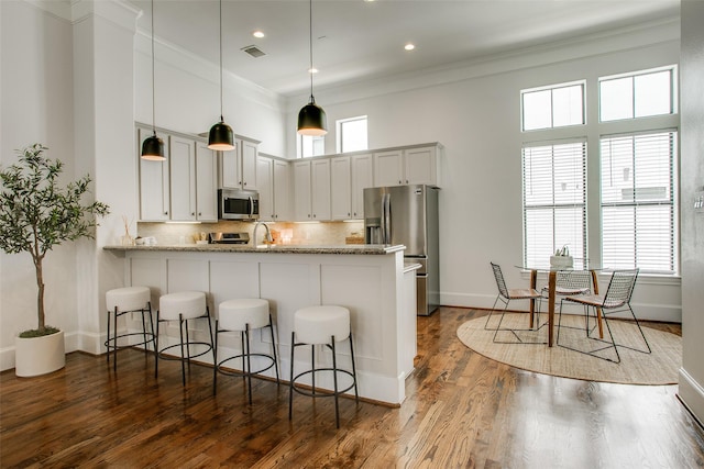 2123 Diversey St, Dallas, TX 75201 - kitchen with stainless steel appliances, a breakfast bar area, a peninsula, crown molding, and decorative backsplash