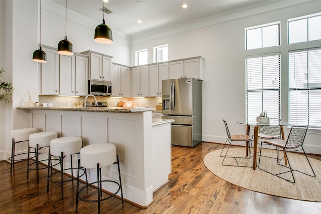 2123 Diversey St, Dallas, TX 75201 - kitchen with stainless steel appliances, a peninsula, a kitchen breakfast bar, baseboards, and tasteful backsplash