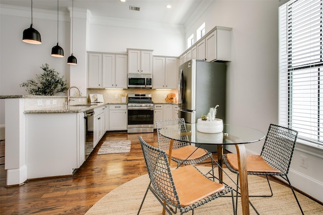 2123 Diversey St, Dallas, TX 75201 - kitchen with stainless steel appliances, a sink, wood finished floors, tasteful backsplash, and crown molding