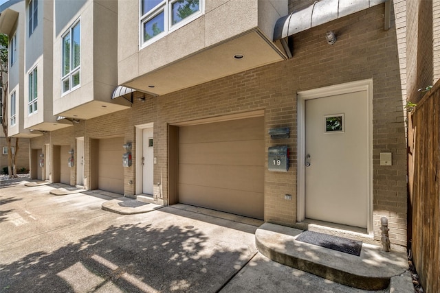 4100 Travis St Unit 19, Dallas, TX 75204 - view of exterior entry with brick siding, driveway, and a garage