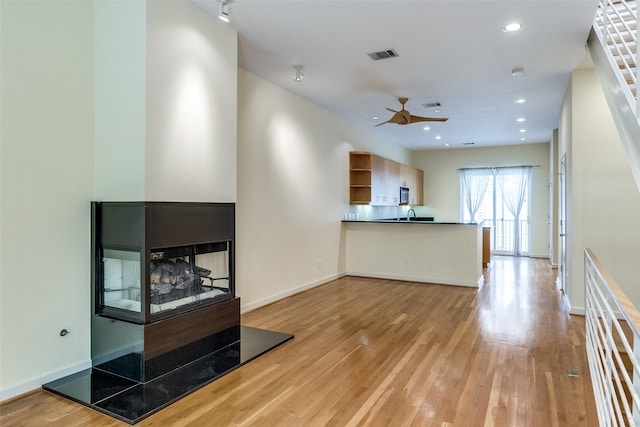 4100 Travis St Unit 19, Dallas, TX 75204 - unfurnished living room featuring a ceiling fan, wood finished floors, a multi sided fireplace, recessed lighting, and baseboards