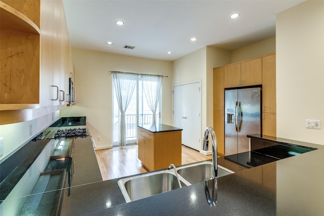 4100 Travis St Unit 19, Dallas, TX 75204 - kitchen with stainless steel fridge, light wood-style flooring, dark countertops, light brown cabinetry, and a sink