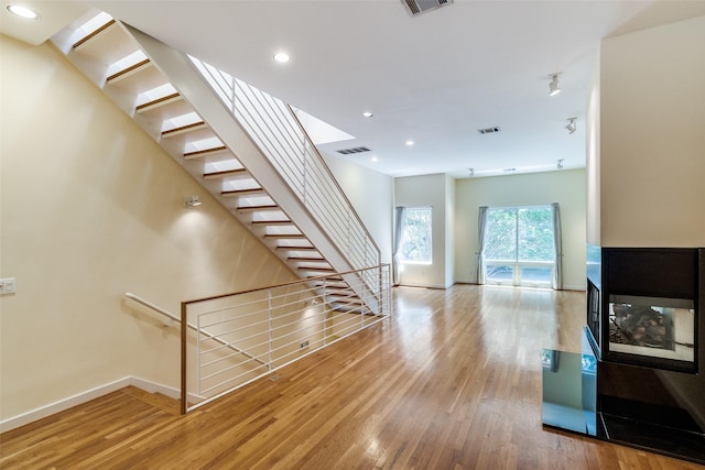 4100 Travis St Unit 19, Dallas, TX 75204 - unfurnished living room featuring baseboards, wood finished floors, recessed lighting, and stairs