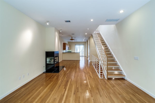 4100 Travis St Unit 19, Dallas, TX 75204 - unfurnished living room with ceiling fan, wood finished floors, stairs, baseboards, and recessed lighting