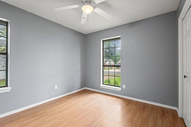 613 Locust St S, Sulphur Springs, TX 75482 - spare room with wood finished floors, healthy amount of natural light, baseboards, a ceiling fan, and a textured ceiling