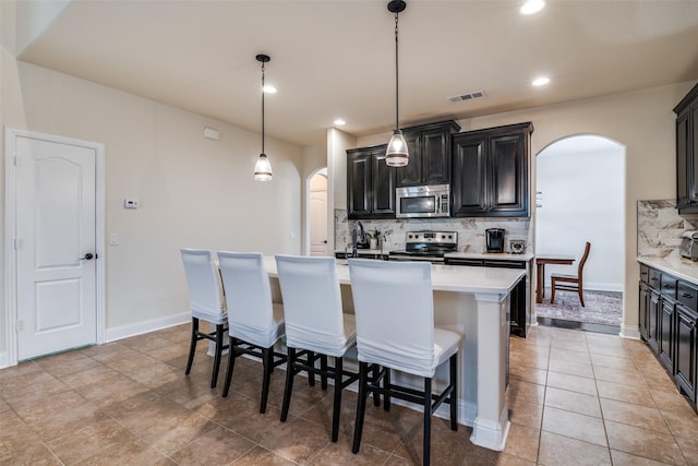4301 Spruce Rd, Melissa, TX 75454 - kitchen with arched walkways, appliances with stainless steel finishes, backsplash, an island with sink, and recessed lighting