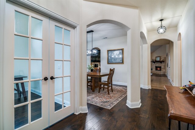 4301 Spruce Rd, Melissa, TX 75454 - entrance foyer with dark wood-style floors, french doors, a lit fireplace, baseboards, and arched walkways
