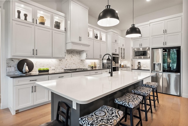 1804 Rockwood Ln, Mansfield, TX 76063 - kitchen featuring appliances with stainless steel finishes, light wood-style flooring, a breakfast bar area, and tasteful backsplash