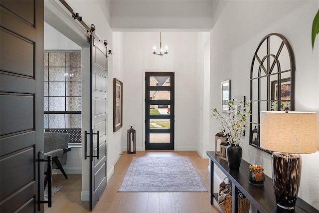 1804 Rockwood Ln, Mansfield, TX 76063 - foyer with a barn door, light wood-type flooring, a chandelier, a towering ceiling, and baseboards