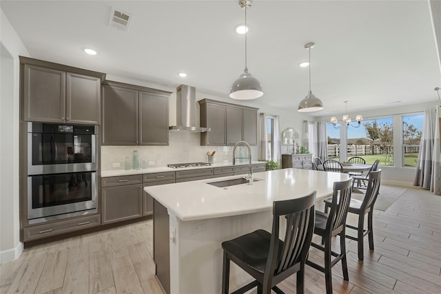 10020 Crestview Dr, Denton, TX 76207 - kitchen featuring a sink, wall chimney range hood, appliances with stainless steel finishes, a kitchen bar, and an island with sink