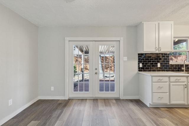 1103 Bowman St, Irving, TX 75060 - kitchen with wood finished floors, french doors, a textured ceiling, tasteful backsplash, and white cabinets