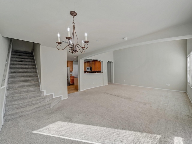 1159 Landon Ln, Allen, TX 75013 - unfurnished living room with a chandelier, light colored carpet, stairway, arched walkways, and baseboards