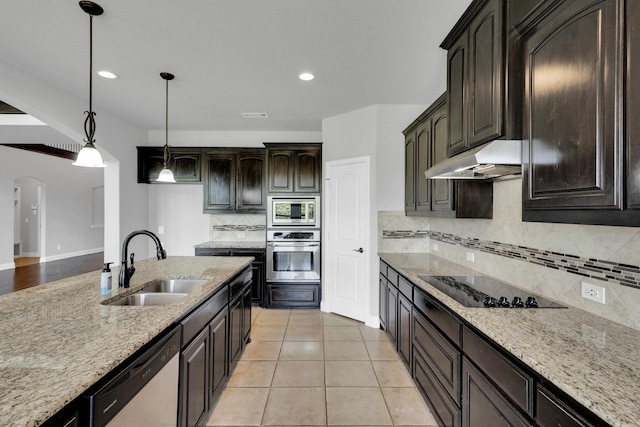 1708 Stillwater Dr, Burleson, TX 76028 - kitchen featuring stainless steel appliances, a sink, under cabinet range hood, light stone countertops, and arched walkways