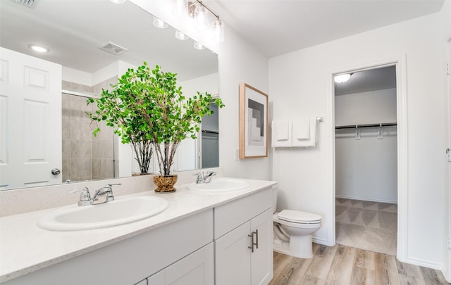 2402 Carlow Ln, Lowry Crossing, TX 75407 - bathroom with double vanity, tiled shower, toilet, a walk in closet, and wood finished floors
