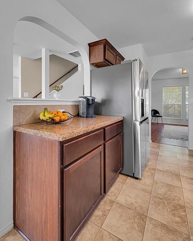 6608 Costa Dr, Waco, TX 76712 - kitchen with arched walkways, stainless steel fridge with ice dispenser, and light tile patterned floors