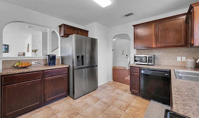 6608 Costa Dr, Waco, TX 76712 - kitchen with appliances with stainless steel finishes, arched walkways, decorative backsplash, a sink, and light countertops