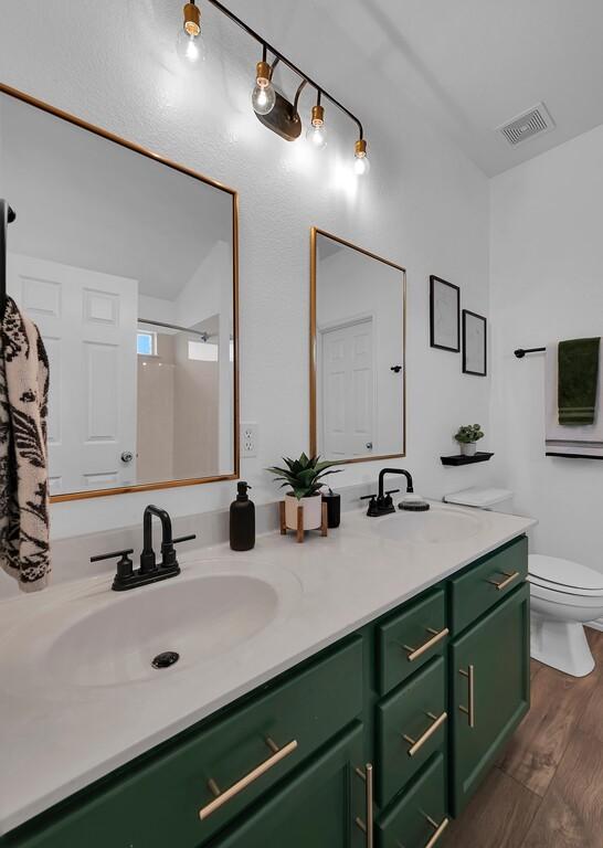 6608 Costa Dr, Waco, TX 76712 - full bath with double vanity, toilet, wood finished floors, and a shower
