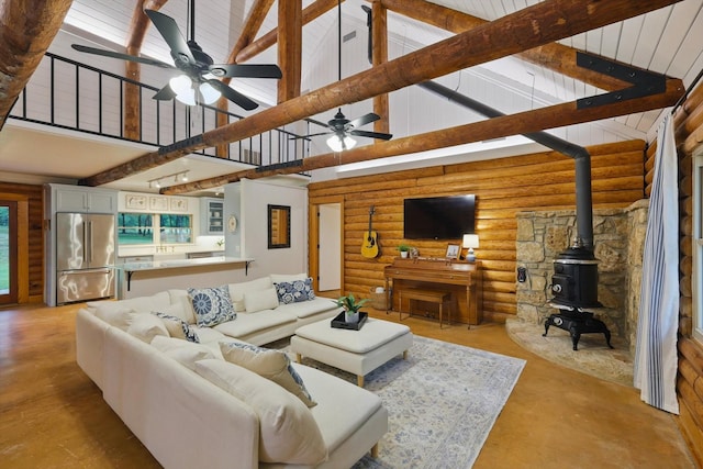 127 Pleasant Valley Ln, Weatherford, TX 76087 - living area with high vaulted ceiling, a wood stove, a ceiling fan, concrete flooring, and log walls