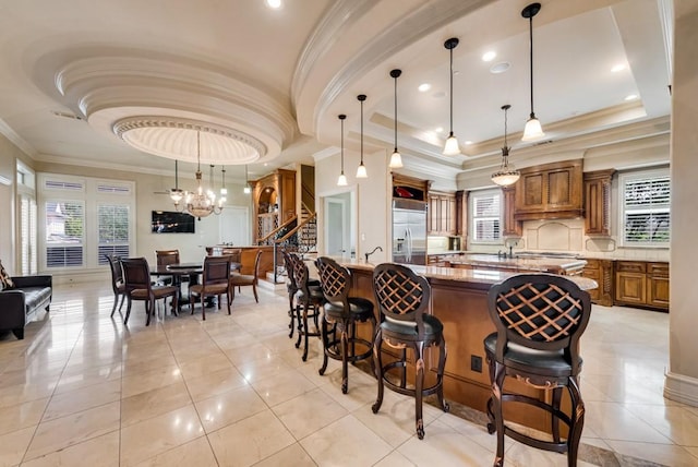 1751 Bison Meadow Ln, Heath, TX 75032 - kitchen featuring brown cabinets, built in refrigerator, a spacious island, plenty of natural light, and crown molding