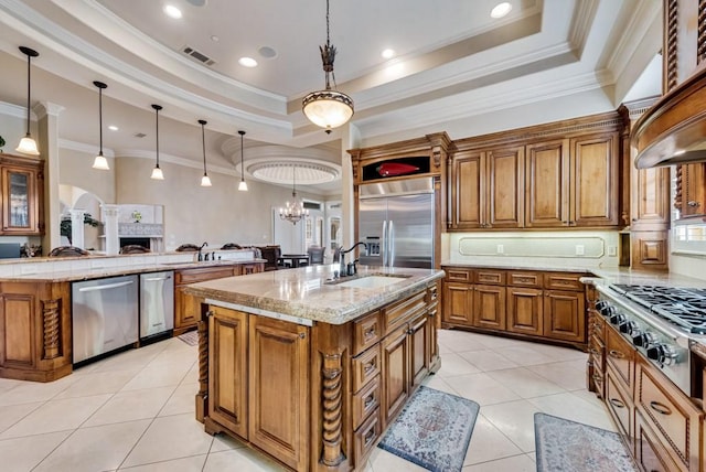 1751 Bison Meadow Ln, Heath, TX 75032 - kitchen with appliances with stainless steel finishes, an island with sink, a sink, a tray ceiling, and brown cabinetry