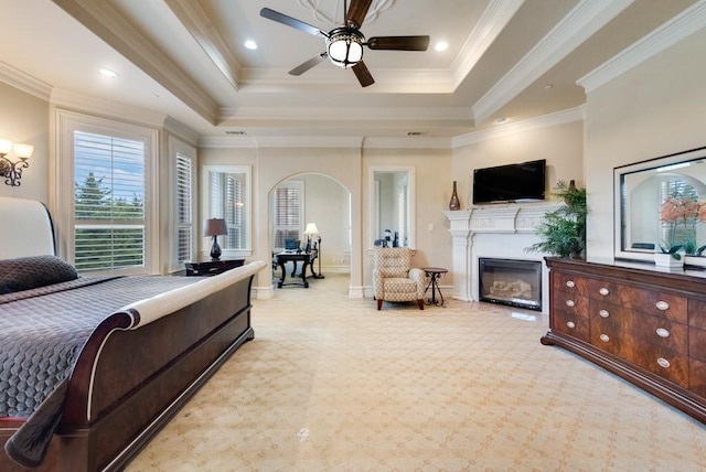 1751 Bison Meadow Ln, Heath, TX 75032 - carpeted bedroom featuring a tray ceiling, arched walkways, a glass covered fireplace, baseboards, and crown molding