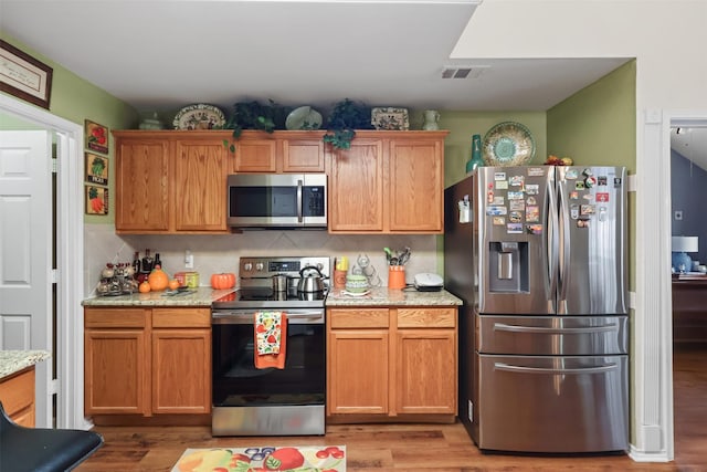 408 Autumn Park Park, Fort Worth, TX 76140 - kitchen with appliances with stainless steel finishes, light wood finished floors, tasteful backsplash, and light stone countertops