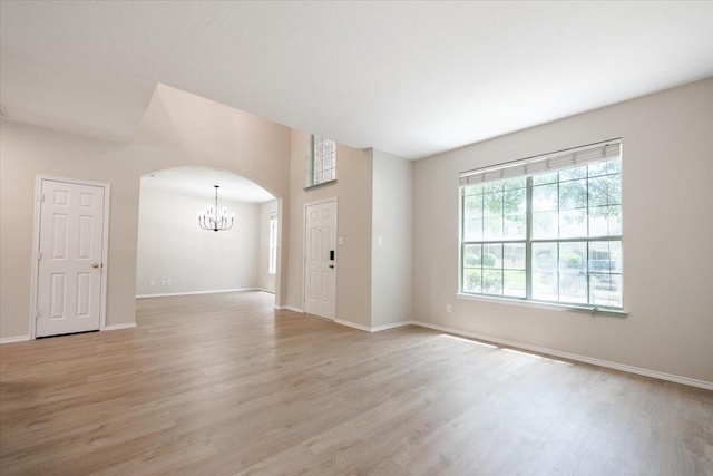 5900 Pine Meadow Ln, Mckinney, TX 75070 - empty room featuring a chandelier, light wood-type flooring, arched walkways, and baseboards