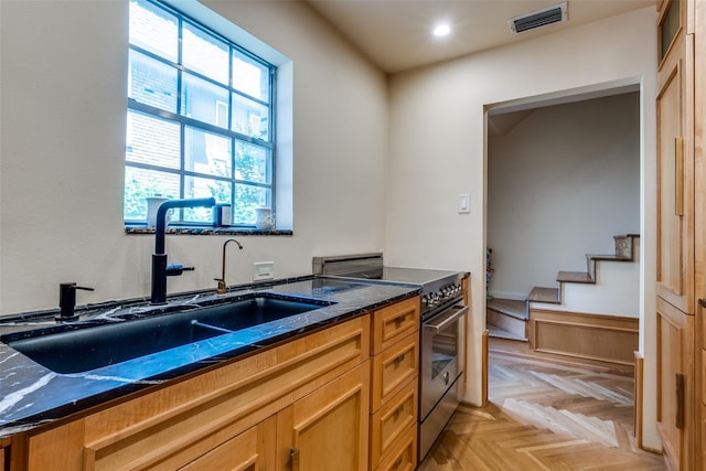 4306 Buena Vista St Unit 106F, Dallas, TX 75205 - kitchen featuring a sink, high end range, dark stone counters, brown cabinets, and recessed lighting