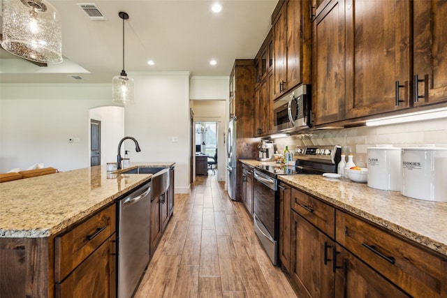 1308 Green Ridge Rd, Weatherford, TX 76085 - kitchen featuring appliances with stainless steel finishes, a sink, a kitchen island with sink, light stone countertops, and crown molding