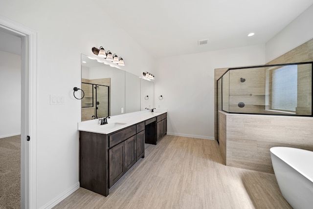411 Solo Ridge Dr, Waxahachie, TX 75167 - bathroom with a stall shower, a soaking tub, double vanity, wood finished floors, and recessed lighting