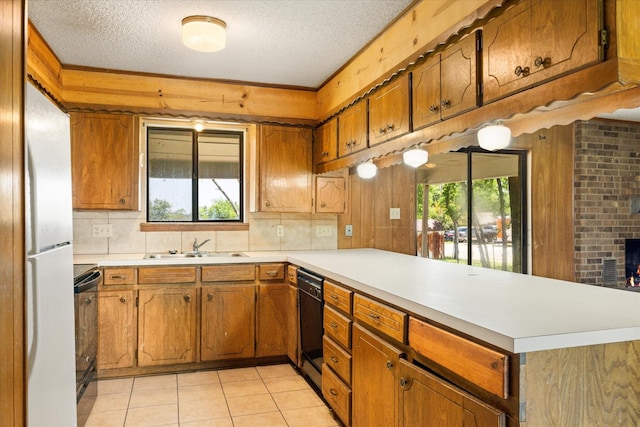 1023 Holmes Dr, Granbury, TX 76048 - kitchen with a peninsula, brown cabinetry, black dishwasher, a textured ceiling, and light countertops