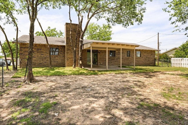 1023 Holmes Dr, Granbury, TX 76048 - rear view of house with a patio area, brick siding, and a chimney