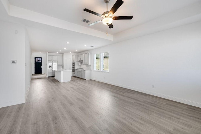 1220 Toro Ln, Fort Worth, TX 76052 - unfurnished living room featuring light wood-style floors, recessed lighting, ceiling fan, baseboards, and a raised ceiling