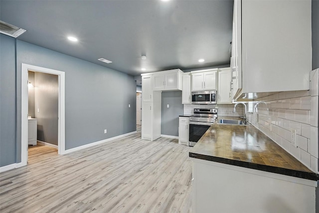 906 S Willow St, Sherman, TX 75090 - kitchen with appliances with stainless steel finishes, white cabinetry, light wood-style floors, tasteful backsplash, and recessed lighting